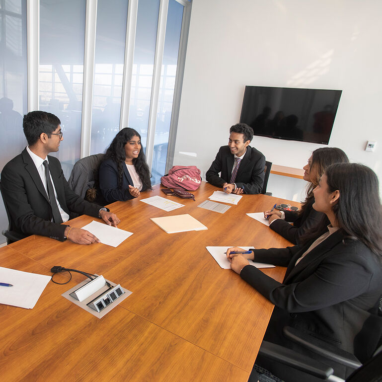 Group of RBS students in professional attire sitting around a conference table